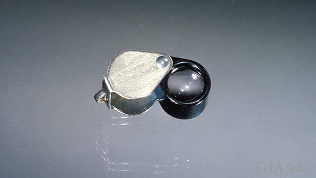 灰色を背景にして置かれている10倍ルーペ。