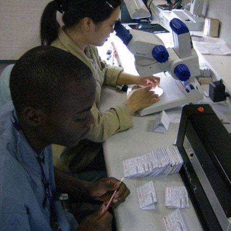 A technician works with a local trainee on the use of rough diamond planning machines. 