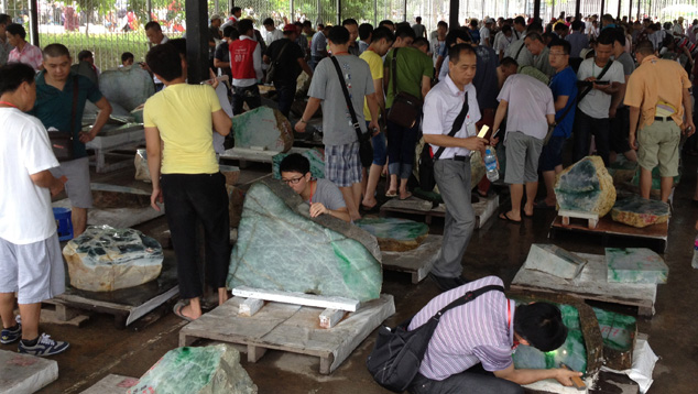 在内比都举办的 2013 年春季拍卖市场上，潜在买家们正在仔细检查大块硬玉。 买家人数多达 5000 人，大多来自中国，他们在拍卖会上使用特殊的手电筒来检验产品，以确定其半透明度。 图片由 Stanley Chu, On Tung Jewellery, Hong Kong（香港安珠宝公司朱裕伦）友情提供。