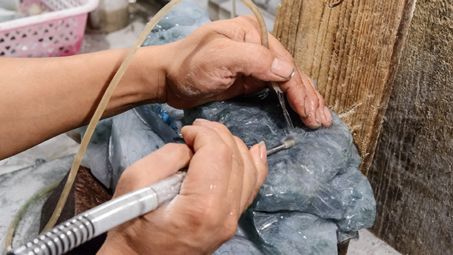 雕刻时，带有金属钻头的软轴和水一起润滑硬玉原石