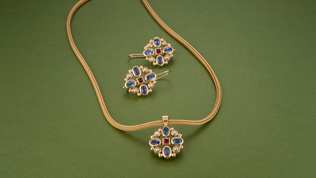 マッチするペンダントとイヤリングは、中央にあるルビーの周りを４つの真珠と楕円形のタンザナイトが交互にセッティングされているのが特徴である。