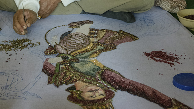 Gem painter picks up stone with tweezers