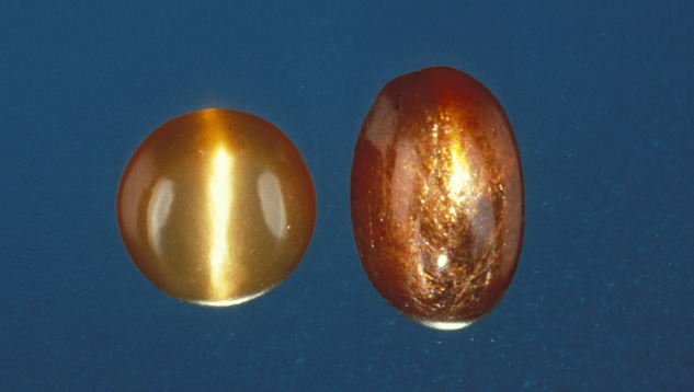 この2.39カラットの アヴェンチュレッセンスが見られる日長石（右）は、インド南部、タミル・ナドゥ州で産出されたものです。 その隣には、同じ地域産出のキャッツアイ効果を生じるムーンストーンが並べられています（左）。 - Shane F. McClure（シェーン F. マクルーア）