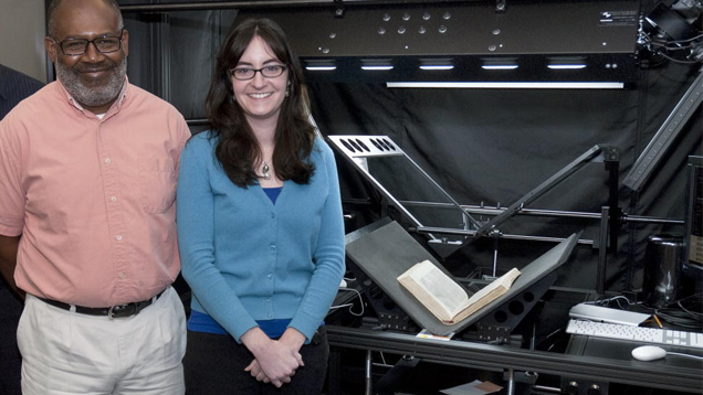 两位研究馆员站在高科技图书扫描仪前。