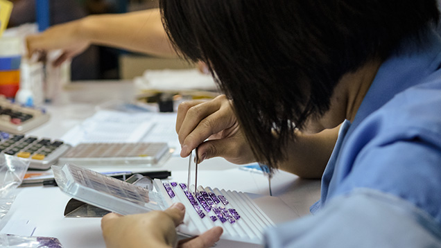 工作人员将宝石与一套模版对照进行分级