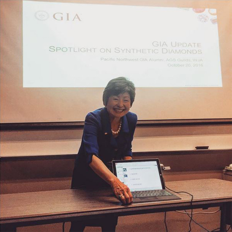 教室では出席者が前方のスピーカーに耳を傾けている。