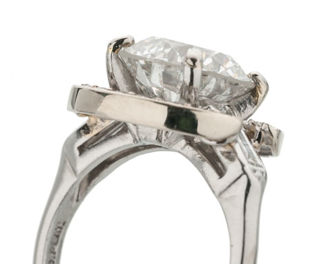 Side view of a platinum solitaire ring set with a round brilliant center diamond featuring prongs that have been repaired using white gold solder.