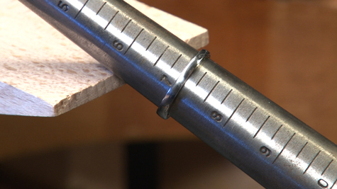 Metal ring mandrel resting against a bench pin
