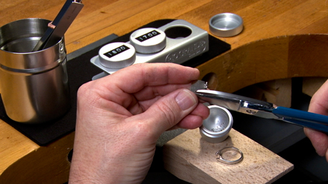 Jeweler working at the bench; dedicated containers for platinum tools are visible