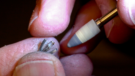 Hard, cone-shaped wheel and platinum polishing compound polishing the inside of a platinum ring’s peg setting