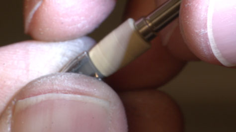 Tray containing five compartments of platinum polishing compound in various grits, along with five adjacent compartments containing attachments for working with the compound at the bench