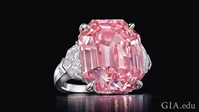 The large pink center stone of this ring is a cut-cornered rectangular-cut diamond. It is flanked by colorless diamonds.