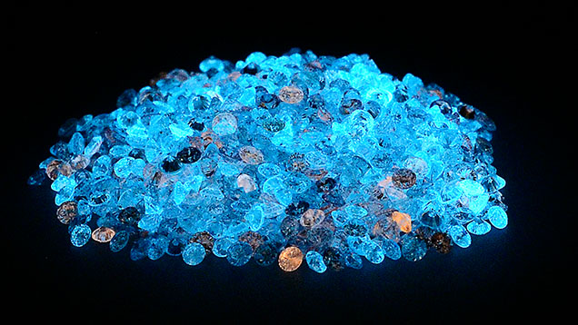 Many loose laboratory-grown diamonds glowing under short-wave uv light 