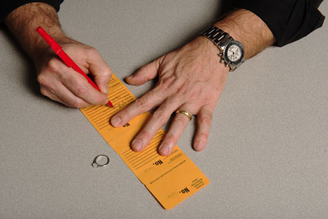 Close-up of jeweler writing customer sizing information on job envelope