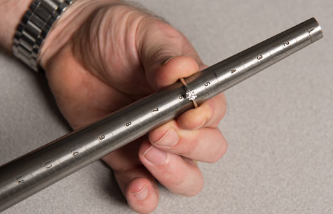 Close-up of jeweler checking size of platinum solitaire on tapered ring mandrel