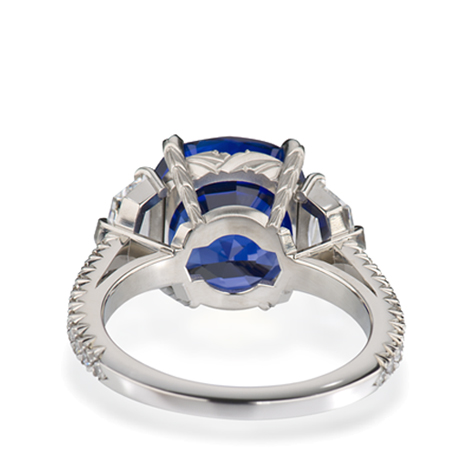 铂金戒指底部视图，可以看到一颗蓝宝石主石两侧饰有数颗钻石，镶嵌于戒圈之中。